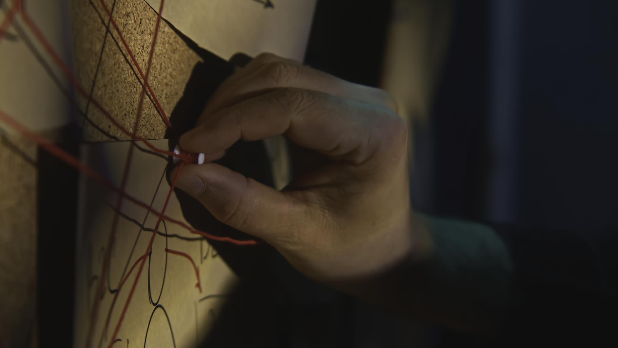 Hands stitching a geometric motif under LED lamp